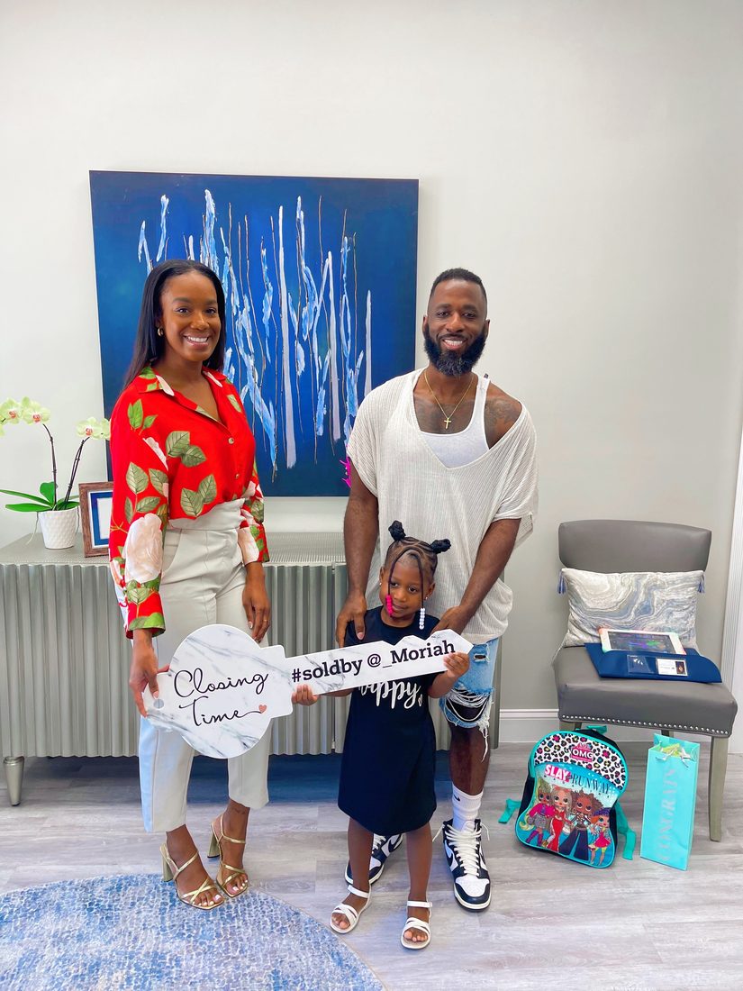 Family celebrating their new home purchase with a Diversify Real Estate Group closing sign